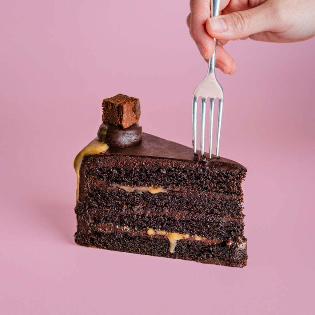A person putting a fork into a slice of chocolate cake